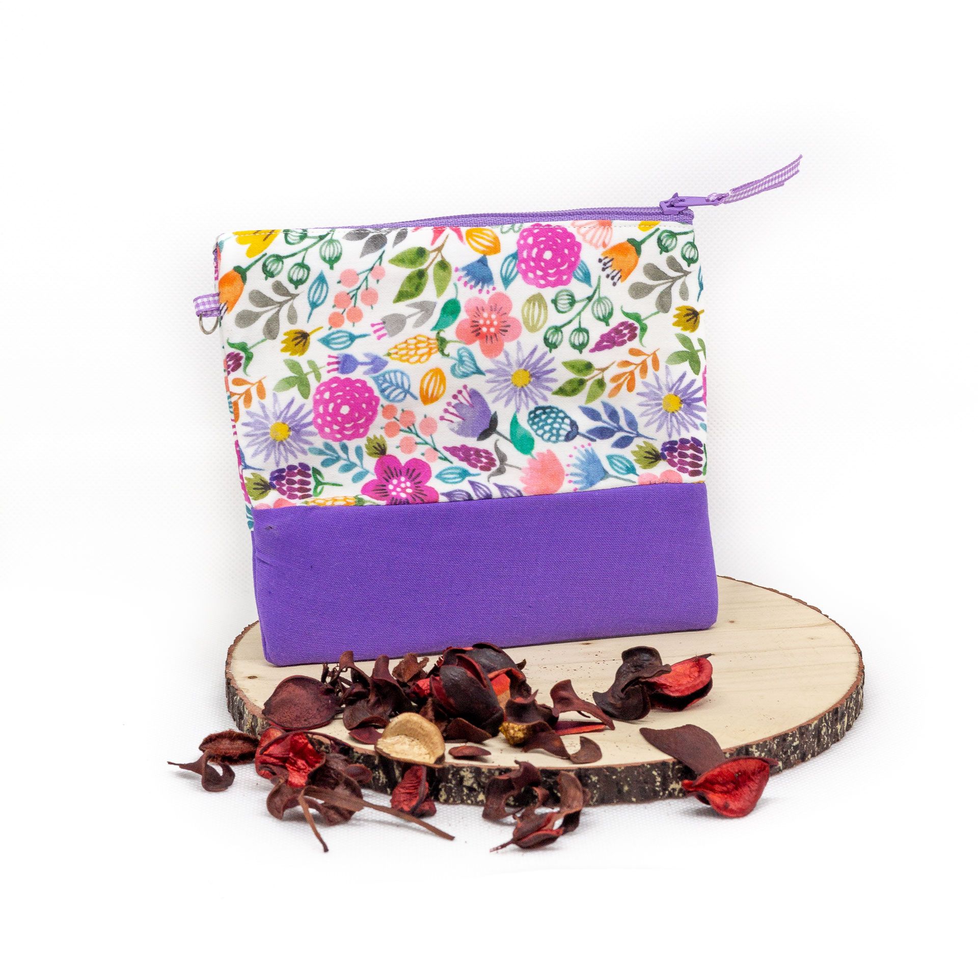 Bolsa artesanal con estampado floral y cremallera Bolsa artesanal floral morada en escena decorativa natural