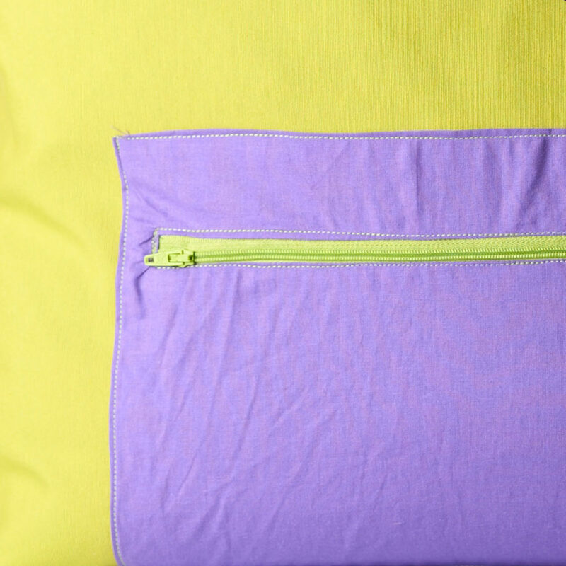 Detalle bolsillo con cremallera bolso tote Detalle del bolsillo exterior con cremallera en lila del bolso tote