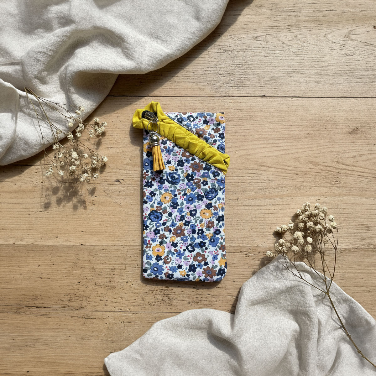 Funda multiusos de tela con estampado floral azul Funda multiusos de tela con estampado floral sobre fondo de madera