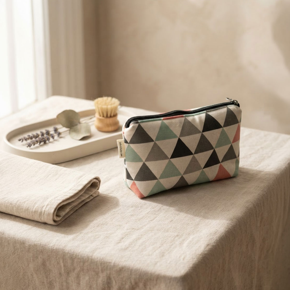 Neceser de tela con cremallera y estampado geométrico Neceser de tela con cremallera y estampado geométrico sobre una superficie textil
