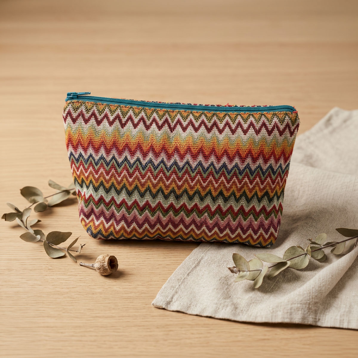 Neceser de tela con cremallera y estampado zigzag Neceser de tela con cremallera y estampado de zigzag multicolor sobre una mesa